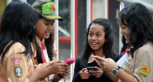 Melindungi Anak Indonesia Dari Jebakan Media Sosial Anak-anak sekolah di Indonesia membuka Facebook di perangkat seluler mereka. Sumber Getty Images