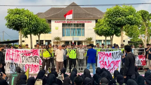 Ratusan massa yang tergabung dalam aliansi Wonosobo Melawan menggelar aksi unjuk rasa di depan Kantor Bupati Wonosobo, Jumat (26/6/2026). Massa menyampaikan tuntutan terkait sejumlah isu nasional dan daerah, mulai dari program pemerintah pusat, infrastruktur, BUMD, hingga transparansi anggaran. Sumber: Tribunnews.com