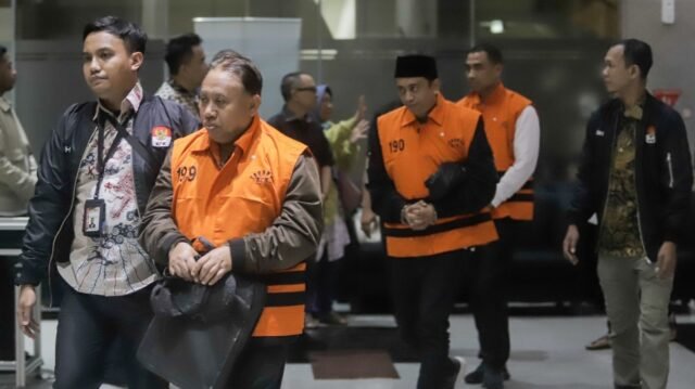 Rektor Universitas Jenderal Soedirman (Unsoed) bersama tersangka lainnya berjalan menuju mobil tahanan usai menjalani pemeriksaan pasca terjaring operasi tangkap tangan (OTT) di Gedung KPK, Jakarta, Sabtu (22/8/2026) dini hari. [Suara.com/Alfian Winanto]