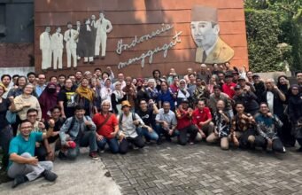 FIAD Minta Pemerintah Jamin Kesejahteraan, Kemerdekaan, dan Perlindungan Profesi Guru Puluhan peserta pertemuan FIAD berfoto bersama sambil mengepalkan tangan di depan mural Indonesia Menggugat, Bandung