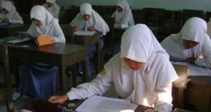 Menanti Kejelasan dan Transparansi Skor TKA Siswi SMA berjilbab mengerjakan soal ujian di ruang kelas