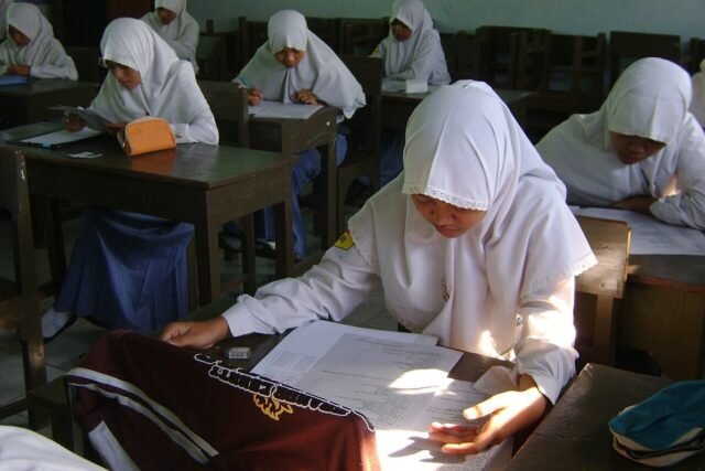 Siswi SMA berjilbab mengerjakan soal ujian di ruang kelas